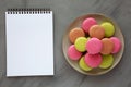 Colorful Homemade French Macarons on a Plate, blank notepad, top view. Flat lay, overhead, from above