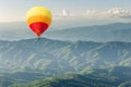 Colorful hot air balloon above forest mountain