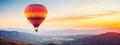 Colorful hot air balloon flying early in the morning over the mountain. Scenic sunrise or sunset view Royalty Free Stock Photo