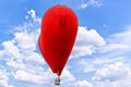 Heart-shaped hot air balloon flying over a blue sky with white clouds Royalty Free Stock Photo
