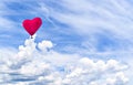 Heart-shaped hot air balloon flying over a blue sky with white clouds Royalty Free Stock Photo