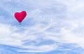 Heart-shaped hot air balloon flying over a blue sky with white clouds Royalty Free Stock Photo