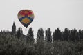 Colorful Hot-Air Balloon in the Sky over Vegetation near Italian Church Tower Royalty Free Stock Photo