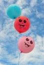 three smiley balls against a background of blue sky with clouds.