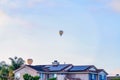 Colorful hot air balloons against cloudy blue sky over house with solar panels Royalty Free Stock Photo