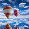 Colorful hot air balloons flies above calm lake