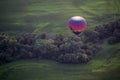 A colorful hot air balloons flies above the Iowa countryside.