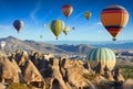 Colorful hot air balloons fly in blue sky over amazing rocky valley in Cappadocia, Turkey