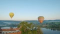 Colorful hot air balloons fly over the medieval castle and lake in the morning fog. Maneuverable flight and power loop