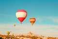 Colorful hot air balloons flying near Uchisar castle at sunrise, Cappadocia, Turkey