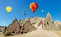 Colorful hot air balloons flying over volcanic cliffs at Cappadocia