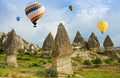 Colorful hot air balloons flying over volcanic cliffs at Cappadocia