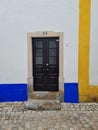 Colorful house, yellow and blue wall, black door in Obidos portugal cobblestone street