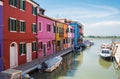 Colorful houses along the canal with parked boats on Burano island, Venice, Italy. Attractive famous travel destination Royalty Free Stock Photo