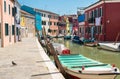 Colorful houses along the canal with parked boats on Burano island, Venice, Italy. Attractive famous travel destination Royalty Free Stock Photo