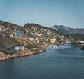 Colorful houses dot the hillsides of the fishing town of Kangaamiut, West Greenland. Icebergs from Kangia glacier in Royalty Free Stock Photo