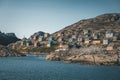 Colorful houses dot the hillsides of the fishing town of Kangaamiut, West Greenland. Icebergs from Kangia glacier in Royalty Free Stock Photo