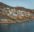 Colorful houses dot the hillsides of the fishing town of Kangaamiut, West Greenland. Icebergs from Kangia glacier in Royalty Free Stock Photo