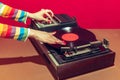 Colorful image of female hands spinning retro vinyl record player like a dj isolated over red background Royalty Free Stock Photo