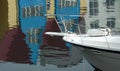 Colorful impressionistic reflection in harbour water, houses and front of a sailboat