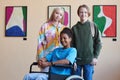 Colorful inclusive group of teenagers smiling at camera visiting art gallery