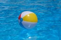 Colorful inflatable beach ball floating in swimming pool on background of blue water Royalty Free Stock Photo