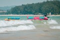 colorful inflatable boats and one jetski for playful beach sport close to seashore line, anchored at tropical sea, waves, side