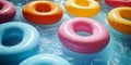 Colorful inflatable pool tubes floating on clear blue water in sunlight Royalty Free Stock Photo