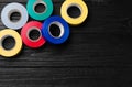 Colorful insulating tapes on black wooden table, flat lay. Space for text