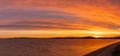 Colorful and intense sunset over the coean and a sand and pebble beach