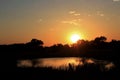 Colorful Kansas sky with clouds and a reflection on a farm pond and tree silhouettes that`s bright and colorful out in the country Royalty Free Stock Photo