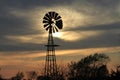 Colorful Kansas sky at Sunset with clouds, tree`s and a Windmill silhouette out in the country. Royalty Free Stock Photo