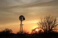 Colorful Kansas sky at Sunset with clouds, tree`s and a Windmill silhouette out in the country. Royalty Free Stock Photo