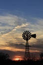 Colorful Kansas Sunset with clouds, tree`s and a Windmill silhouette out in the country. Royalty Free Stock Photo