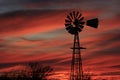 Colorful Kansas Sunset with a Windmill and tree silhouettes.