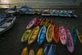 Colorful kayaks and boats on the beach at sunset.