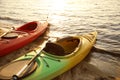 Colorful kayaks with paddles near water on river beach at sunset. Summer camp activity Royalty Free Stock Photo