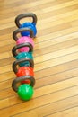 Colorful kettlebells in a row on the wooden floor in a gym Royalty Free Stock Photo