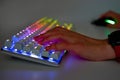 Colorful keyboard with RGB light and hand, blurred background. The player`s hands on the keyboard and mouse, close-up. The concep Royalty Free Stock Photo