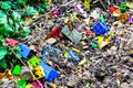 Colorful kids plastic cube toys thrown on the ground. Dirty kids toys on the soil.