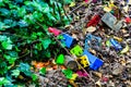 Colorful kids plastic cube toys thrown on the ground. Dirty kids toys on the soil.