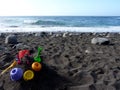 Colorful kids sand toys on black Atlantic Ocean beach with blue sea in the background Royalty Free Stock Photo