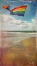 A colorful kite flying against a blue sky over a sandy beach Royalty Free Stock Photo