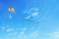 Colorful kite flying in the blue sky through the clouds Royalty Free Stock Photo