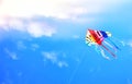 Colorful kite flying in the blue sky through the clouds Royalty Free Stock Photo