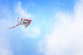 Colorful kite flying in the blue sky through the clouds Royalty Free Stock Photo