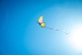 Colorful kite with long tail flying in the blue sky against the sun, copy space Royalty Free Stock Photo