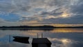 Sunrise on the lake. Boat, sun, clouds and reflection on water. Royalty Free Stock Photo