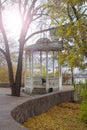 Colorful landscape. A deserted autumn city park with a rotunda, gazebo and fallen leaves, trees, an empty bench on a sunny day.
