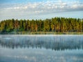 A colorful landscape of a forest on the shore of a lake reflected in the water. Early morning. Beginning of autumn Royalty Free Stock Photo